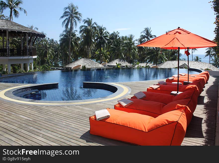 A tropical resort with sun loungers on deck and a swimming pool in the center. A tropical resort with sun loungers on deck and a swimming pool in the center.