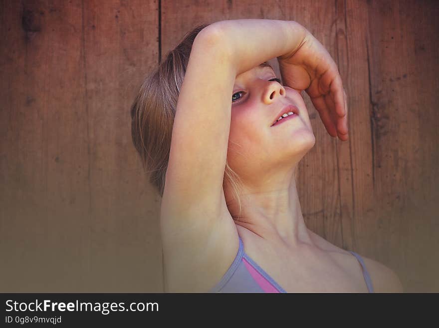 A portrait of a ballerina girl posing in front of a wooden background.