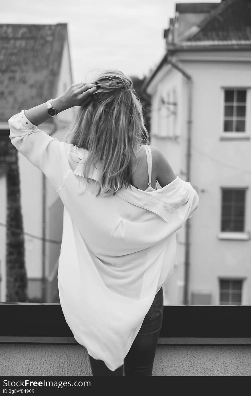 A woman standing on the roof with shirt falling off her shoulder. A woman standing on the roof with shirt falling off her shoulder.