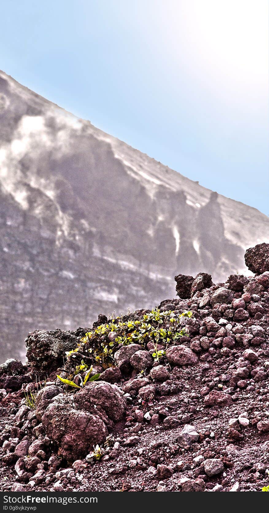 A photograph divided into three layers in the foreground is the flat part with the peitre and in the background the interior of the ancient volcano volcano and then the white of the sky.