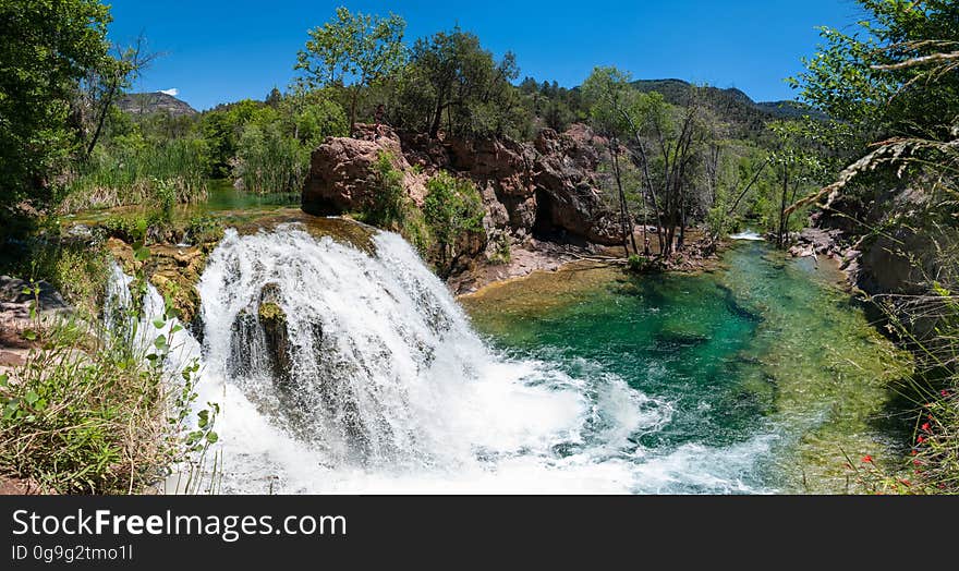 This large, natural waterfall on Fossil Creek is the destination of an easy, one mile hike on Waterfall Trail. A large, deep pool at the base of the fall is a popular swimming hole. Fossil Creek produces 20,000 gallons of water a minute from a series of springs at the bottom of a 1,600 foot deep canyon. This permanent water source has created a stunningly beautiful, green riparian zone rich with flora and fauna at the bottom of this arid canyon in Arizona&#x27;s high desert. Travertine deposits encase whatever happens to fall into the streambed, forming the fossils for which the area is named. These deposits create deep pools along the length of the creek, providing opportunities to find more secluded swimming holes than the popular pool at the waterfall. Fossil Creek is one of two &quot;Wild and Scenic&quot; rivers in Arizona. This designation was achieved when the Irving power plant was decommissioned, and removal of flume and dam on the creek allowed the creek to flow free. Increasing popularity has led to the Coconino and Tonto National Forests to implement a parking permit reservation system in 2016. Reserved parking permits allow visitors to have a parking spot available in their chosen parking lot. Many visitors drive two or three hours to get to the creek. The final descent to the creek at the bottom of a canyon is on an extremely rough, rocky jeep road. In prior years, the area would often be closed to entry when it reached capacity, and potential visitors would be turned away after the long, difficult drive. Photo by Deborah Lee Soltesz, May 12, 2016. For trail and recreation information, see Fossil Creek, Fossil Springs Wilderness, and the Coconino National Forest. This large, natural waterfall on Fossil Creek is the destination of an easy, one mile hike on Waterfall Trail. A large, deep pool at the base of the fall is a popular swimming hole. Fossil Creek produces 20,000 gallons of water a minute from a series of springs at the bottom of a 1,600 foot deep canyon. This permanent water source has created a stunningly beautiful, green riparian zone rich with flora and fauna at the bottom of this arid canyon in Arizona&#x27;s high desert. Travertine deposits encase whatever happens to fall into the streambed, forming the fossils for which the area is named. These deposits create deep pools along the length of the creek, providing opportunities to find more secluded swimming holes than the popular pool at the waterfall. Fossil Creek is one of two &quot;Wild and Scenic&quot; rivers in Arizona. This designation was achieved when the Irving power plant was decommissioned, and removal of flume and dam on the creek allowed the creek to flow free. Increasing popularity has led to the Coconino and Tonto National Forests to implement a parking permit reservation system in 2016. Reserved parking permits allow visitors to have a parking spot available in their chosen parking lot. Many visitors drive two or three hours to get to the creek. The final descent to the creek at the bottom of a canyon is on an extremely rough, rocky jeep road. In prior years, the area would often be closed to entry when it reached capacity, and potential visitors would be turned away after the long, difficult drive. Photo by Deborah Lee Soltesz, May 12, 2016. For trail and recreation information, see Fossil Creek, Fossil Springs Wilderness, and the Coconino National Forest.