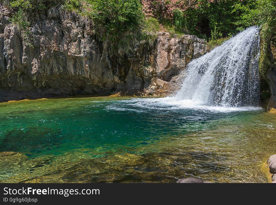 A large, natural waterfall on Fossil Creek is the destination of an easy, one mile hike on Waterfall Trail. A large, deep pool at the base of the fall is a popular swimming hole. Fossil Creek produces 20,000 gallons of water a minute from a series of springs at the bottom of a 1,600 foot deep canyon. This permanent water source has created a stunningly beautiful, green riparian zone rich with flora and fauna at the bottom of this arid canyon in Arizona&#x27;s high desert. Travertine deposits encase whatever happens to fall into the streambed, forming the fossils for which the area is named. These deposits create deep pools along the length of the creek, providing opportunities to find more secluded swimming holes than the popular pool at the waterfall. Fossil Creek is one of two &quot;Wild and Scenic&quot; rivers in Arizona. This designation was achieved when the Irving power plant was decommissioned, and removal of flume and dam on the creek allowed the creek to flow free. Increasing popularity has led to the Coconino and Tonto National Forests to implement a parking permit reservation system in 2016. Reserved parking permits allow visitors to have a parking spot available in their chosen parking lot. Many visitors drive two or three hours to get to the creek. The final descent to the creek at the bottom of a canyon is on an extremely rough, rocky jeep road. In prior years, the area would often be closed to entry when it reached capacity, and potential visitors would be turned away after the long, difficult drive. Photo by Deborah Lee Soltesz, May 4, 2016. For trail and recreation information, see Fossil Creek, Fossil Springs Wilderness, and the Coconino National Forest. A large, natural waterfall on Fossil Creek is the destination of an easy, one mile hike on Waterfall Trail. A large, deep pool at the base of the fall is a popular swimming hole. Fossil Creek produces 20,000 gallons of water a minute from a series of springs at the bottom of a 1,600 foot deep canyon. This permanent water source has created a stunningly beautiful, green riparian zone rich with flora and fauna at the bottom of this arid canyon in Arizona&#x27;s high desert. Travertine deposits encase whatever happens to fall into the streambed, forming the fossils for which the area is named. These deposits create deep pools along the length of the creek, providing opportunities to find more secluded swimming holes than the popular pool at the waterfall. Fossil Creek is one of two &quot;Wild and Scenic&quot; rivers in Arizona. This designation was achieved when the Irving power plant was decommissioned, and removal of flume and dam on the creek allowed the creek to flow free. Increasing popularity has led to the Coconino and Tonto National Forests to implement a parking permit reservation system in 2016. Reserved parking permits allow visitors to have a parking spot available in their chosen parking lot. Many visitors drive two or three hours to get to the creek. The final descent to the creek at the bottom of a canyon is on an extremely rough, rocky jeep road. In prior years, the area would often be closed to entry when it reached capacity, and potential visitors would be turned away after the long, difficult drive. Photo by Deborah Lee Soltesz, May 4, 2016. For trail and recreation information, see Fossil Creek, Fossil Springs Wilderness, and the Coconino National Forest.