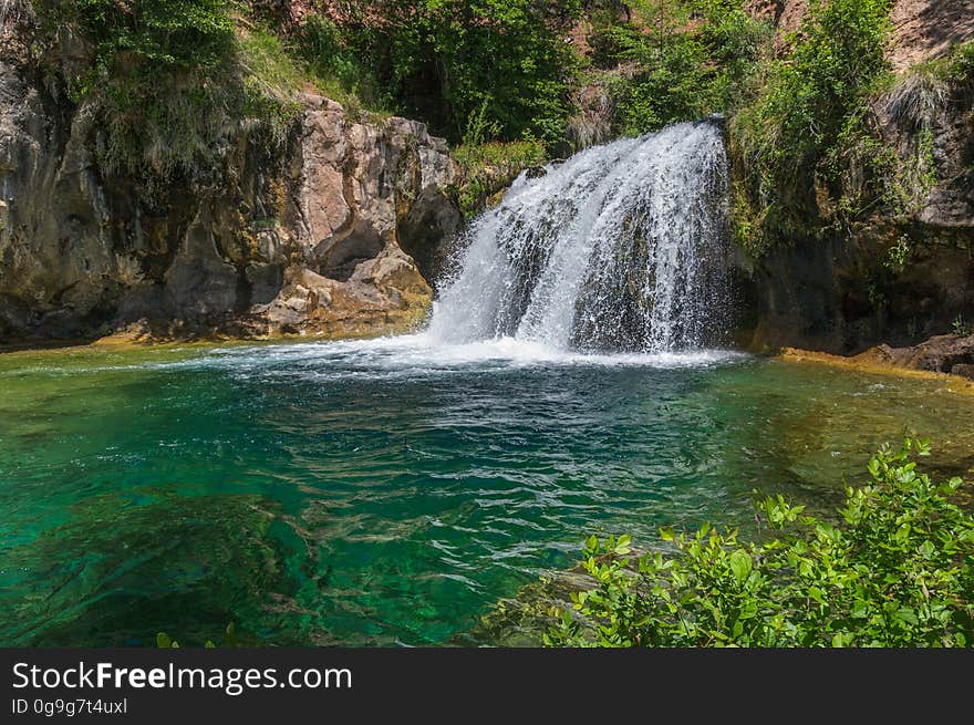 A large, natural waterfall on Fossil Creek is the destination of an easy, one mile hike on Waterfall Trail. A large, deep pool at the base of the fall is a popular swimming hole. Fossil Creek produces 20,000 gallons of water a minute from a series of springs at the bottom of a 1,600 foot deep canyon. This permanent water source has created a stunningly beautiful, green riparian zone rich with flora and fauna at the bottom of this arid canyon in Arizona&#x27;s high desert. Travertine deposits encase whatever happens to fall into the streambed, forming the fossils for which the area is named. These deposits create deep pools along the length of the creek, providing opportunities to find more secluded swimming holes than the popular pool at the waterfall. Fossil Creek is one of two &quot;Wild and Scenic&quot; rivers in Arizona. This designation was achieved when the Irving power plant was decommissioned, and removal of flume and dam on the creek allowed the creek to flow free. Increasing popularity has led to the Coconino and Tonto National Forests to implement a parking permit reservation system in 2016. Reserved parking permits allow visitors to have a parking spot available in their chosen parking lot. Many visitors drive two or three hours to get to the creek. The final descent to the creek at the bottom of a canyon is on an extremely rough, rocky jeep road. In prior years, the area would often be closed to entry when it reached capacity, and potential visitors would be turned away after the long, difficult drive. Photo by Deborah Lee Soltesz, May 4, 2016. For trail and recreation information, see Fossil Creek, Fossil Springs Wilderness, and the Coconino National Forest. A large, natural waterfall on Fossil Creek is the destination of an easy, one mile hike on Waterfall Trail. A large, deep pool at the base of the fall is a popular swimming hole. Fossil Creek produces 20,000 gallons of water a minute from a series of springs at the bottom of a 1,600 foot deep canyon. This permanent water source has created a stunningly beautiful, green riparian zone rich with flora and fauna at the bottom of this arid canyon in Arizona&#x27;s high desert. Travertine deposits encase whatever happens to fall into the streambed, forming the fossils for which the area is named. These deposits create deep pools along the length of the creek, providing opportunities to find more secluded swimming holes than the popular pool at the waterfall. Fossil Creek is one of two &quot;Wild and Scenic&quot; rivers in Arizona. This designation was achieved when the Irving power plant was decommissioned, and removal of flume and dam on the creek allowed the creek to flow free. Increasing popularity has led to the Coconino and Tonto National Forests to implement a parking permit reservation system in 2016. Reserved parking permits allow visitors to have a parking spot available in their chosen parking lot. Many visitors drive two or three hours to get to the creek. The final descent to the creek at the bottom of a canyon is on an extremely rough, rocky jeep road. In prior years, the area would often be closed to entry when it reached capacity, and potential visitors would be turned away after the long, difficult drive. Photo by Deborah Lee Soltesz, May 4, 2016. For trail and recreation information, see Fossil Creek, Fossil Springs Wilderness, and the Coconino National Forest.