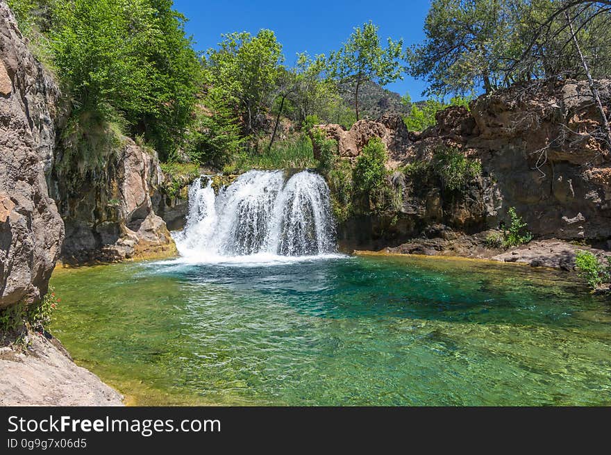 A large, natural waterfall on Fossil Creek is the destination of an easy, one mile hike on Waterfall Trail. A large, deep pool at the base of the fall is a popular swimming hole. Fossil Creek produces 20,000 gallons of water a minute from a series of springs at the bottom of a 1,600 foot deep canyon. This permanent water source has created a stunningly beautiful, green riparian zone rich with flora and fauna at the bottom of this arid canyon in Arizona&#x27;s high desert. Travertine deposits encase whatever happens to fall into the streambed, forming the fossils for which the area is named. These deposits create deep pools along the length of the creek, providing opportunities to find more secluded swimming holes than the popular pool at the waterfall. Fossil Creek is one of two &quot;Wild and Scenic&quot; rivers in Arizona. This designation was achieved when the Irving power plant was decommissioned, and removal of flume and dam on the creek allowed the creek to flow free. Increasing popularity has led to the Coconino and Tonto National Forests to implement a parking permit reservation system in 2016. Reserved parking permits allow visitors to have a parking spot available in their chosen parking lot. Many visitors drive two or three hours to get to the creek. The final descent to the creek at the bottom of a canyon is on an extremely rough, rocky jeep road. In prior years, the area would often be closed to entry when it reached capacity, and potential visitors would be turned away after the long, difficult drive. Photo by Deborah Lee Soltesz, May 4, 2016. For trail and recreation information, see Fossil Creek, Fossil Springs Wilderness, and the Coconino National Forest. A large, natural waterfall on Fossil Creek is the destination of an easy, one mile hike on Waterfall Trail. A large, deep pool at the base of the fall is a popular swimming hole. Fossil Creek produces 20,000 gallons of water a minute from a series of springs at the bottom of a 1,600 foot deep canyon. This permanent water source has created a stunningly beautiful, green riparian zone rich with flora and fauna at the bottom of this arid canyon in Arizona&#x27;s high desert. Travertine deposits encase whatever happens to fall into the streambed, forming the fossils for which the area is named. These deposits create deep pools along the length of the creek, providing opportunities to find more secluded swimming holes than the popular pool at the waterfall. Fossil Creek is one of two &quot;Wild and Scenic&quot; rivers in Arizona. This designation was achieved when the Irving power plant was decommissioned, and removal of flume and dam on the creek allowed the creek to flow free. Increasing popularity has led to the Coconino and Tonto National Forests to implement a parking permit reservation system in 2016. Reserved parking permits allow visitors to have a parking spot available in their chosen parking lot. Many visitors drive two or three hours to get to the creek. The final descent to the creek at the bottom of a canyon is on an extremely rough, rocky jeep road. In prior years, the area would often be closed to entry when it reached capacity, and potential visitors would be turned away after the long, difficult drive. Photo by Deborah Lee Soltesz, May 4, 2016. For trail and recreation information, see Fossil Creek, Fossil Springs Wilderness, and the Coconino National Forest.