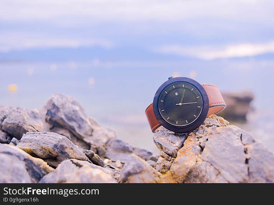 Brown and Black Round Analog Watch on Beige Rocks