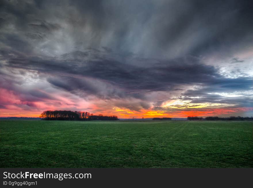 Storm Clouds over Field During Sunset