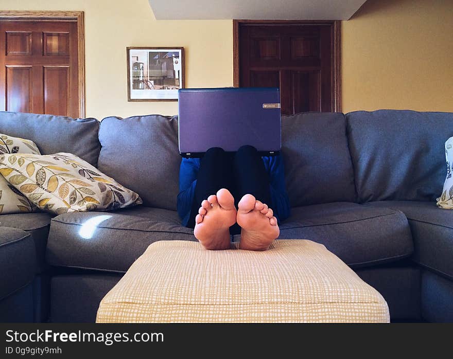 A person sitting on the sofa with a laptop computer. A person sitting on the sofa with a laptop computer.