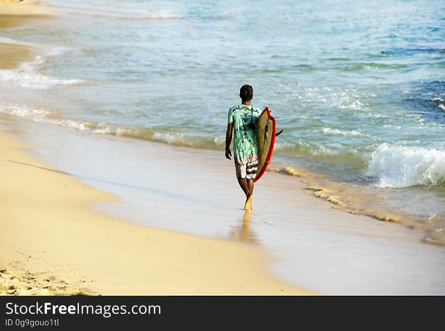 A surfer walking on a beach with his surfboard. A surfer walking on a beach with his surfboard.