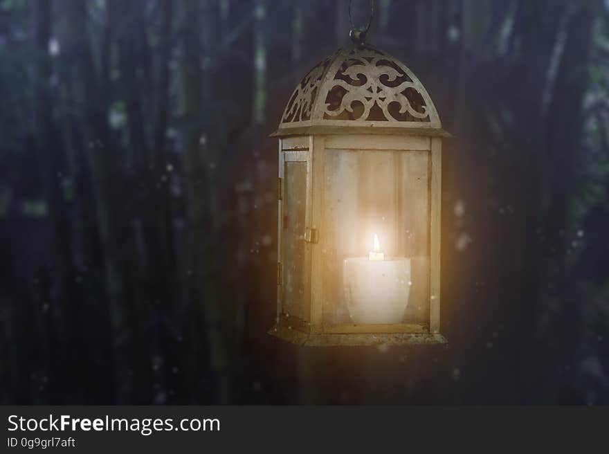 A lantern with a candle burning inside in the night. A lantern with a candle burning inside in the night.