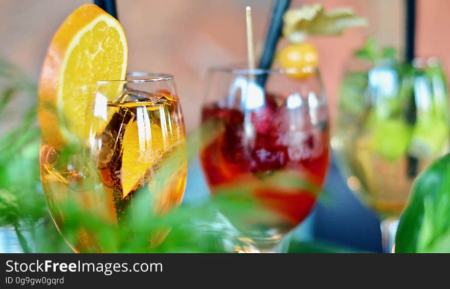 Different colored cocktail drinks garnished with fruit.