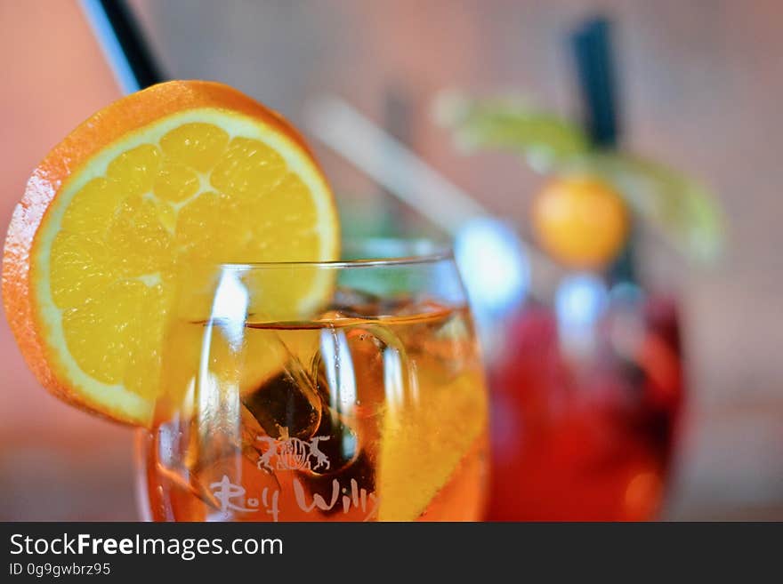 A cocktail in a glass with a slice of orange on the side. A cocktail in a glass with a slice of orange on the side.