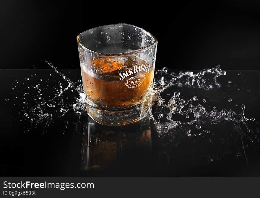 A glass of whisky splashing on black background.