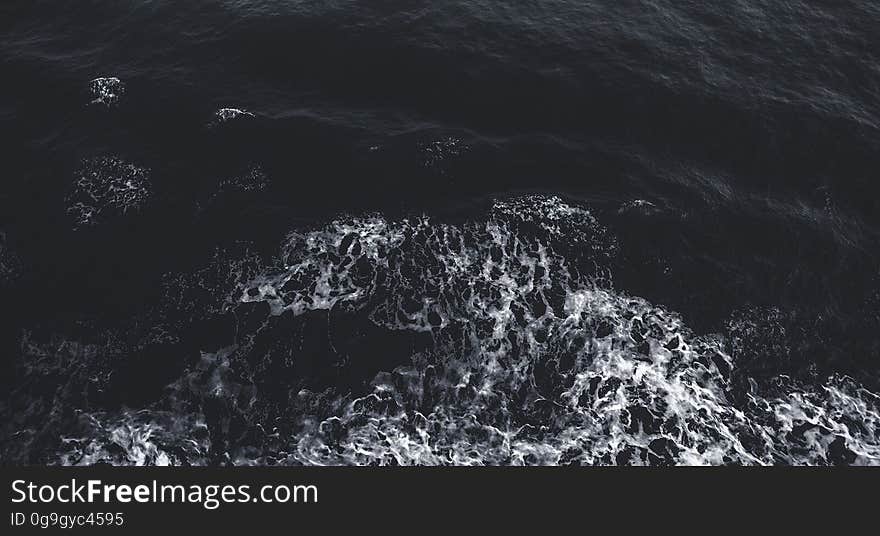 Background created by cold dark sea in the early morning with beginnings of white foam or froth spreading out. Background created by cold dark sea in the early morning with beginnings of white foam or froth spreading out.