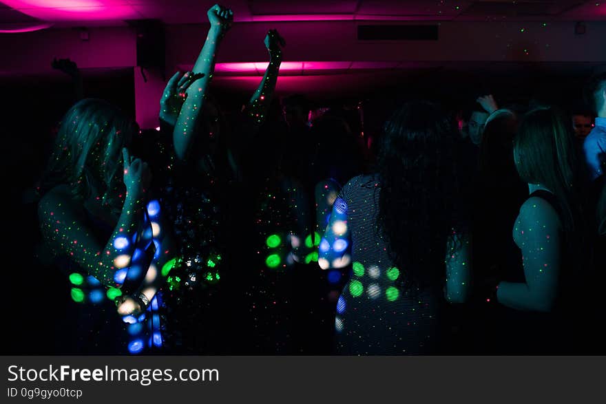 A group of people dancing in the nightclub with colorful lights. A group of people dancing in the nightclub with colorful lights.