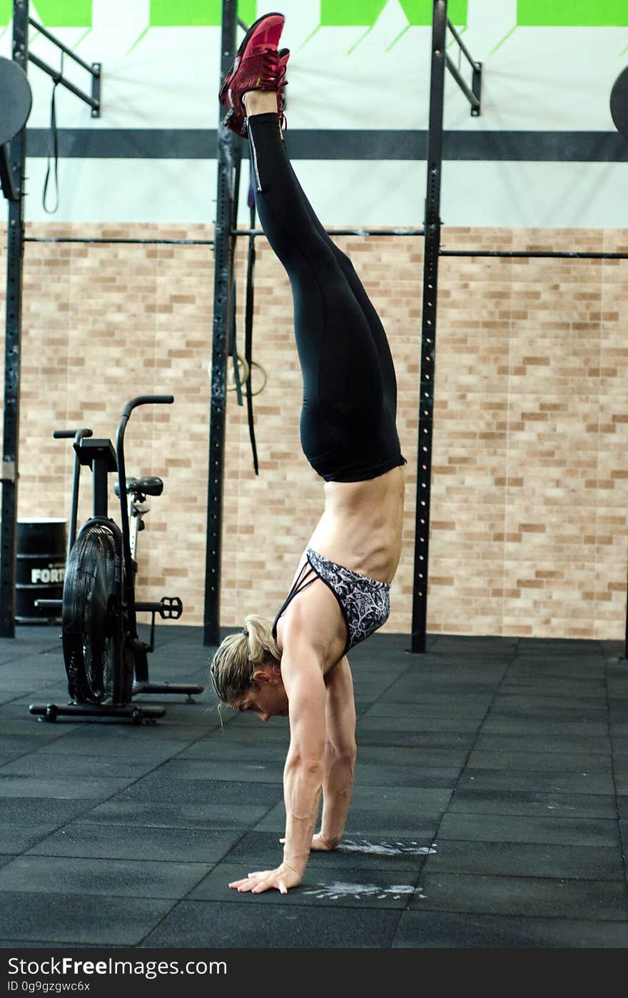 Side view of athletic young woman in gym performing handstand. Side view of athletic young woman in gym performing handstand.