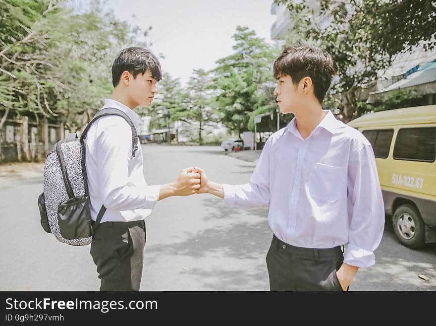 A pair of Asian men shaking hands on the street.