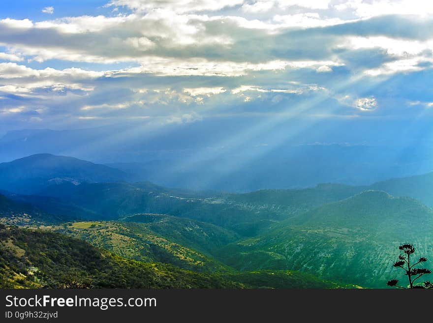 A view over a landscape with rays of lights coming down from the clouds. A view over a landscape with rays of lights coming down from the clouds.