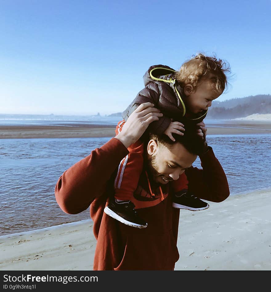 A father and son on the beach with the dad carrying the child on his shoulder. A father and son on the beach with the dad carrying the child on his shoulder.