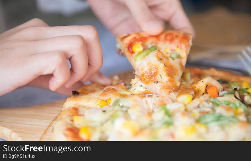 A person taking a slice off pizza from a cutting board. A person taking a slice off pizza from a cutting board.