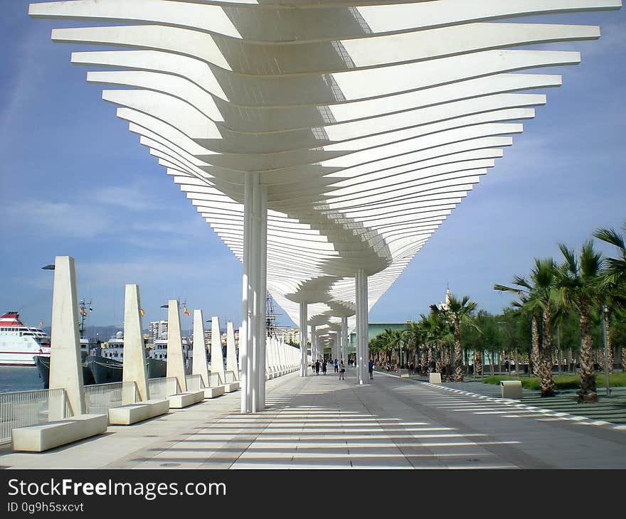 Ultramodern architecture to shield tourists from the sun when embarking from luxury cruise ships stopping in tropical resorts. Palm trees are growing alongside the sheltered walkway. Ultramodern architecture to shield tourists from the sun when embarking from luxury cruise ships stopping in tropical resorts. Palm trees are growing alongside the sheltered walkway.