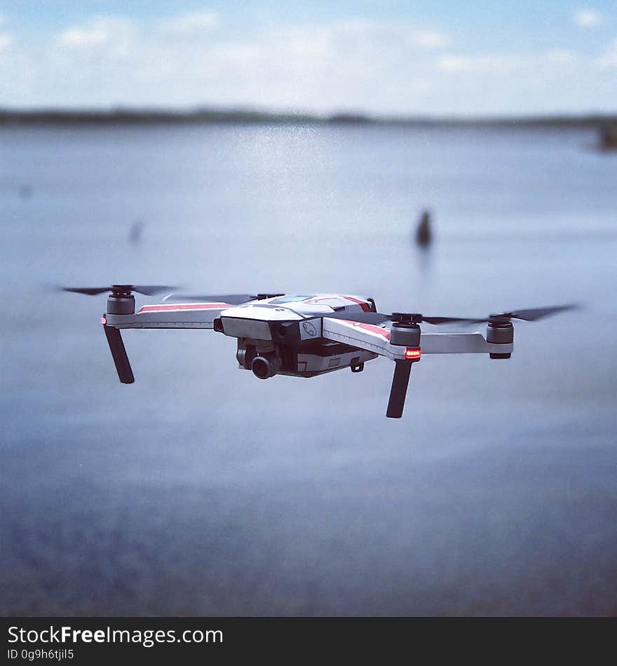 A close up a quadcopter with a camera flying over water. A close up a quadcopter with a camera flying over water.