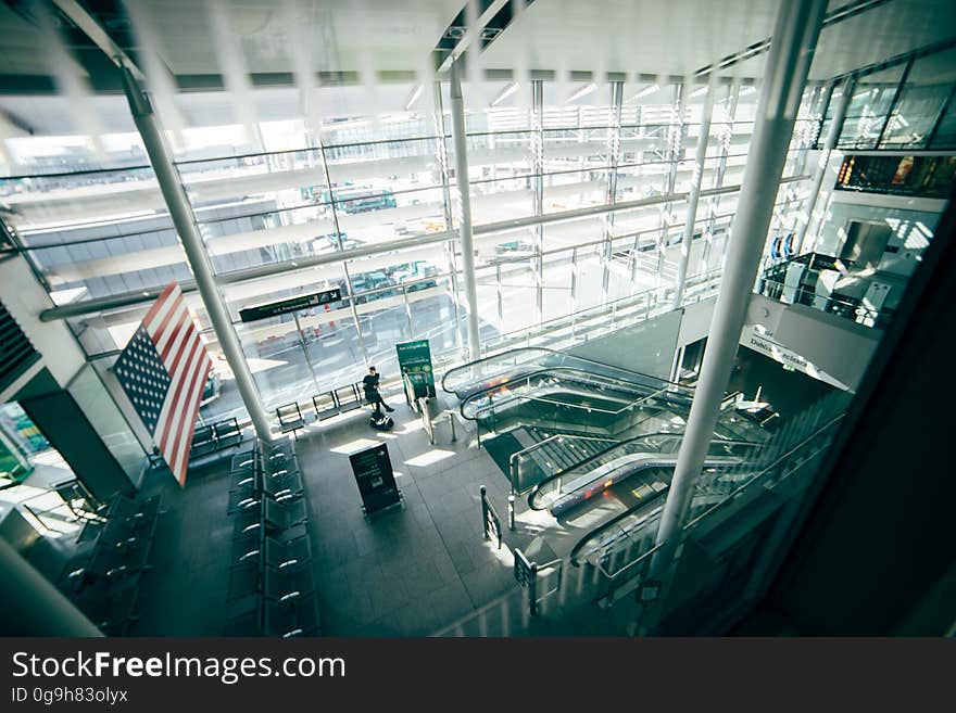 A view inside a commercial building or transit station with stairs and escalators and the American flag. A view inside a commercial building or transit station with stairs and escalators and the American flag.