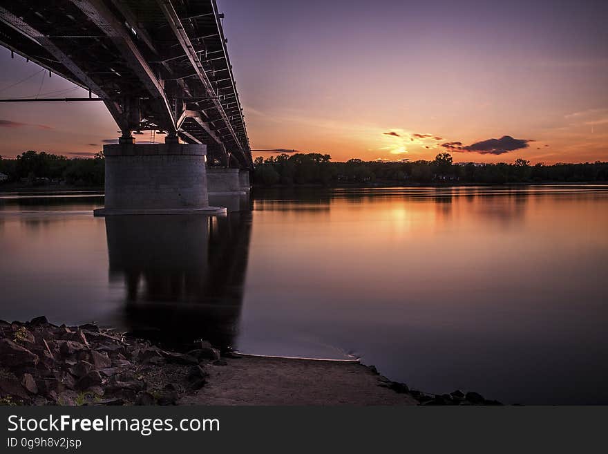 A bridge crossing a river with the sun setting in the background. A bridge crossing a river with the sun setting in the background.