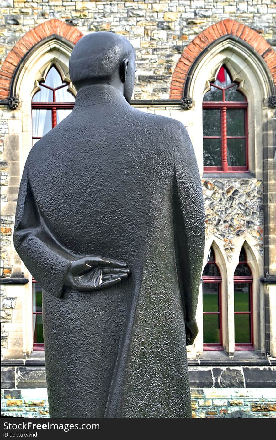 When it comes to sculptures, I am intrigues by details. Was the detail deliberate and part of a message or just a detail that was needed to make the piece complete? Here on the lawn just north of the East Block on Parliament Hill in Ottawa, Ontario, the sculpture of William Lyon Mackenzie King stands looking towards one of the parliament buildings. The sculpture is in a more modern style compared to the many other bronze statues of former prime ministers and other political figures that dot the ground of the parliament. The left hand of Mackenzie King is the detail that interests me the most. Was this a typical posture for the former prime minister? Or is this some commentary on either him or politicians in general? When I was in grade school, it was common for the students to make false promises with one hand behind one&#x27;s back and fingers crossed. While perhaps an appropriate gesture for a politician, is it perhaps is a commentary on King&#x27;s honesty? I prefer to not research the intentions of the artist and let the uncertainly remain. Discovering the true meaning &#x28;or lack of meaning&#x29; in the hand position would result in a reduced interest in the sculpture. Here&#x27;s to Mackenzie King and all others who gazed off into the distance with one hand behind their backs. When it comes to sculptures, I am intrigues by details. Was the detail deliberate and part of a message or just a detail that was needed to make the piece complete? Here on the lawn just north of the East Block on Parliament Hill in Ottawa, Ontario, the sculpture of William Lyon Mackenzie King stands looking towards one of the parliament buildings. The sculpture is in a more modern style compared to the many other bronze statues of former prime ministers and other political figures that dot the ground of the parliament. The left hand of Mackenzie King is the detail that interests me the most. Was this a typical posture for the former prime minister? Or is this some commentary on either him or politicians in general? When I was in grade school, it was common for the students to make false promises with one hand behind one&#x27;s back and fingers crossed. While perhaps an appropriate gesture for a politician, is it perhaps is a commentary on King&#x27;s honesty? I prefer to not research the intentions of the artist and let the uncertainly remain. Discovering the true meaning &#x28;or lack of meaning&#x29; in the hand position would result in a reduced interest in the sculpture. Here&#x27;s to Mackenzie King and all others who gazed off into the distance with one hand behind their backs.