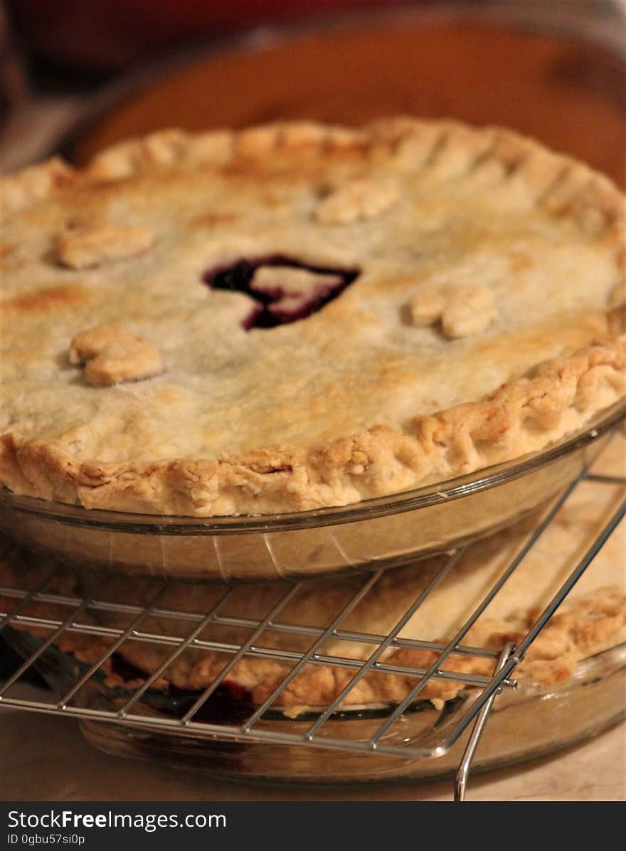 Cherry pie with heart in center, on baking rack with other pies. Cherry pie with heart in center, on baking rack with other pies