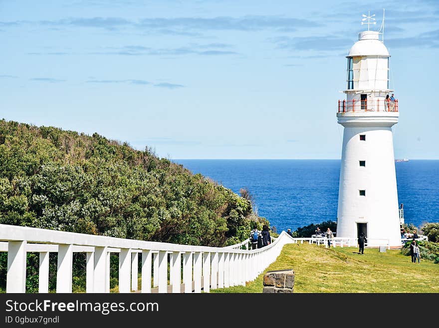 People Standing in Front of White Concrete Lighthouse during Daytime