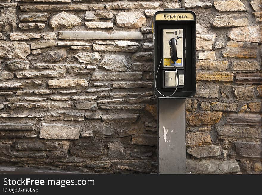 Gray and Black Telephone Booth Standing Near Gray Stone Wall at Daytime