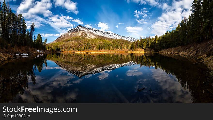 A lake with conifer forest on the shores and a mountain reflecting from the surface. A lake with conifer forest on the shores and a mountain reflecting from the surface.