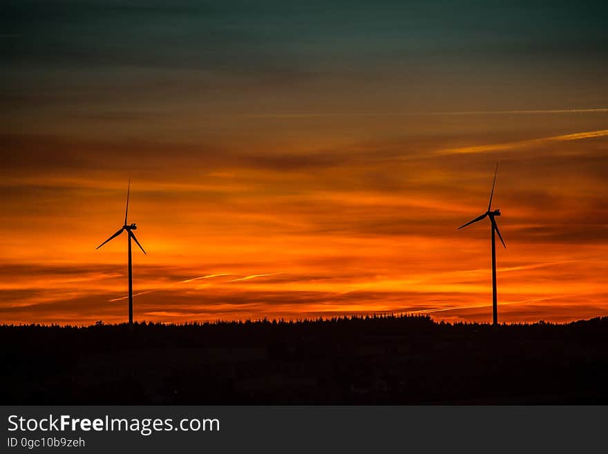 Silhouette of Windmills Under Orange Sunset