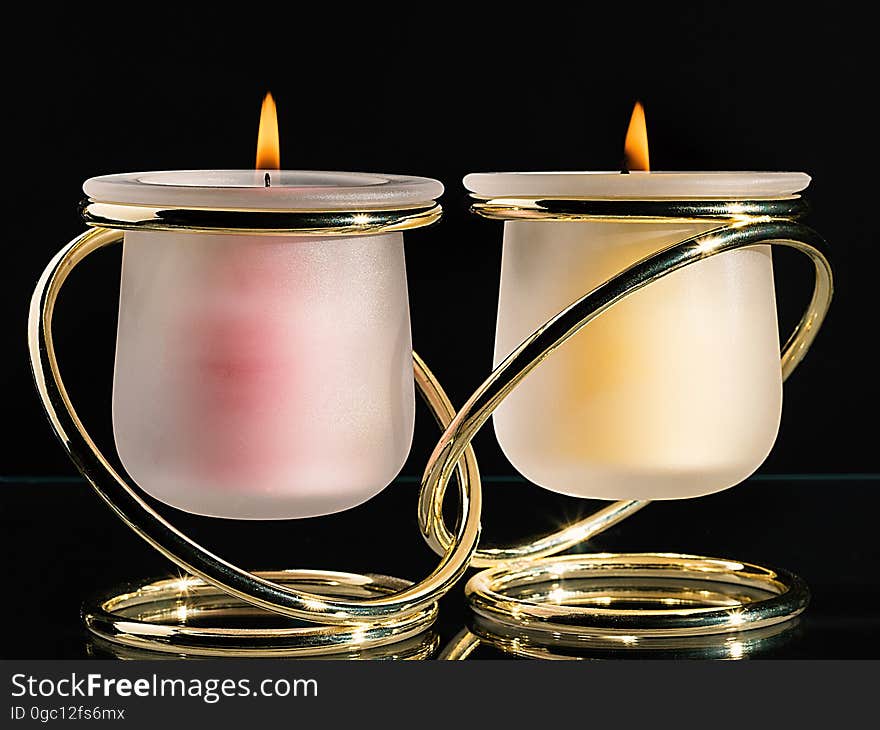 A pair of candles in joined candle holders.