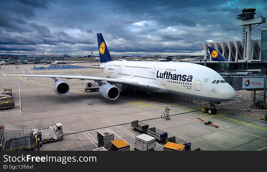 A Lufthansa Airbus A380 with passengers and cargo loading at airport terminal. A Lufthansa Airbus A380 with passengers and cargo loading at airport terminal.