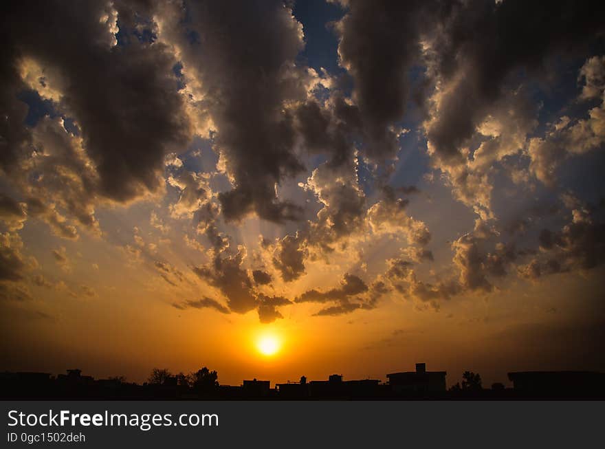 Setting sun in orange skies with grey clouds on horizon. Setting sun in orange skies with grey clouds on horizon.