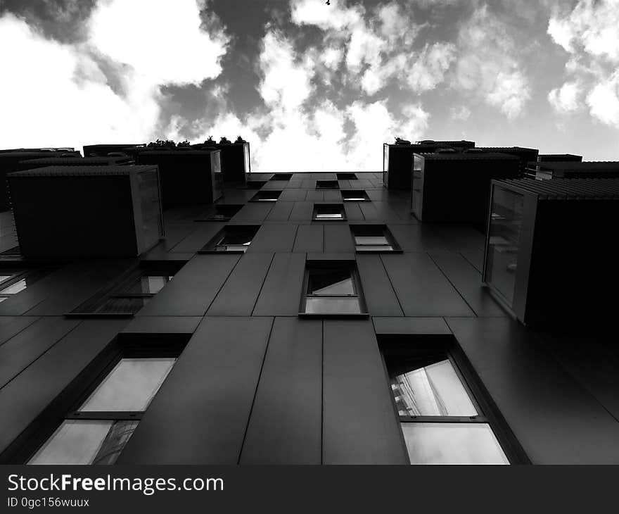 Front of modern apartment building with balconies looking to clouds in sky in black and white. Front of modern apartment building with balconies looking to clouds in sky in black and white.