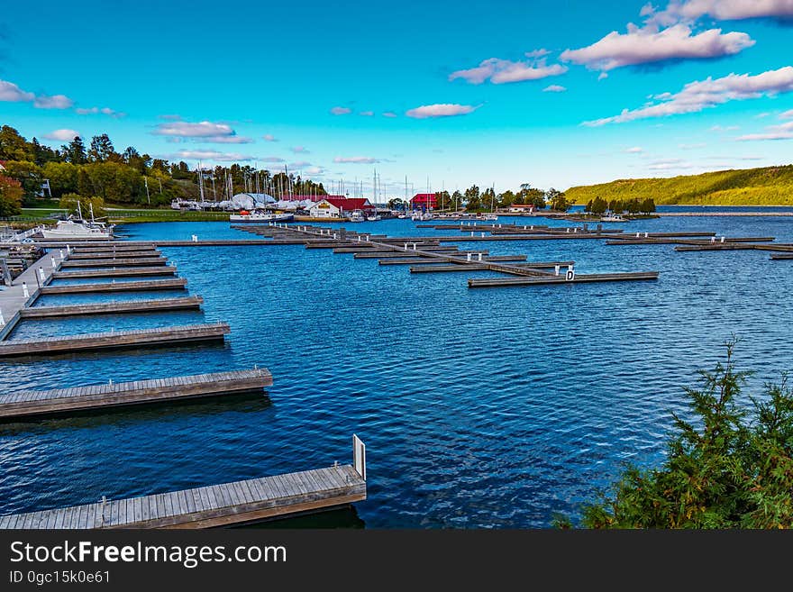 Line of empty wooden docks along waterfront of blue waters against blue skies on sunny day. Line of empty wooden docks along waterfront of blue waters against blue skies on sunny day.