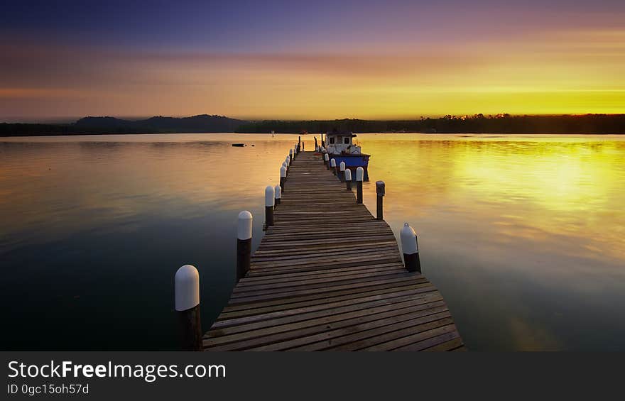 Empty wooden dock leading to clear river at sunset. Empty wooden dock leading to clear river at sunset.