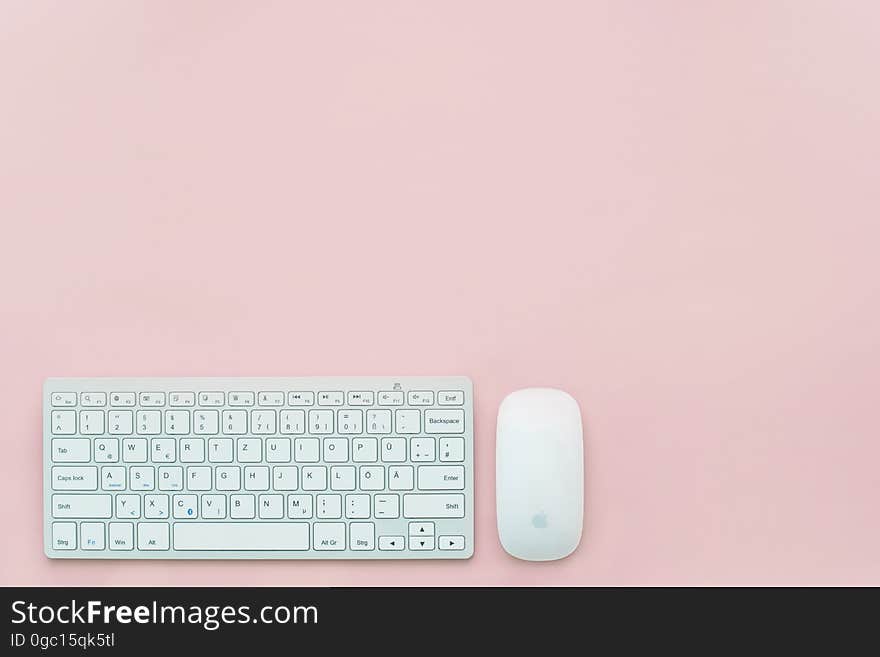 Computer keyboard and mouse with Apple logo on pink. Computer keyboard and mouse with Apple logo on pink.