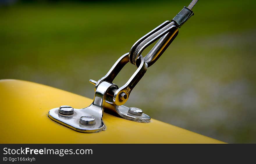 Close up of chrome metal hook and fastener on yellow surface. Close up of chrome metal hook and fastener on yellow surface.