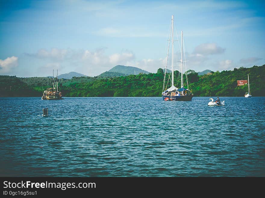 A summer scene with sailboats and paddleboats in the water. A summer scene with sailboats and paddleboats in the water.