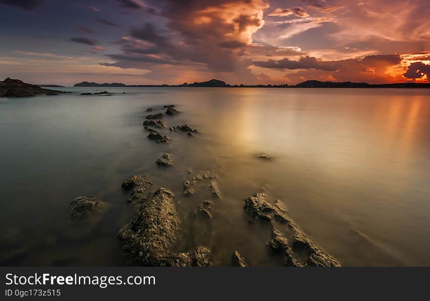 Sunset in cloudy skies over beach on coastline. Sunset in cloudy skies over beach on coastline.