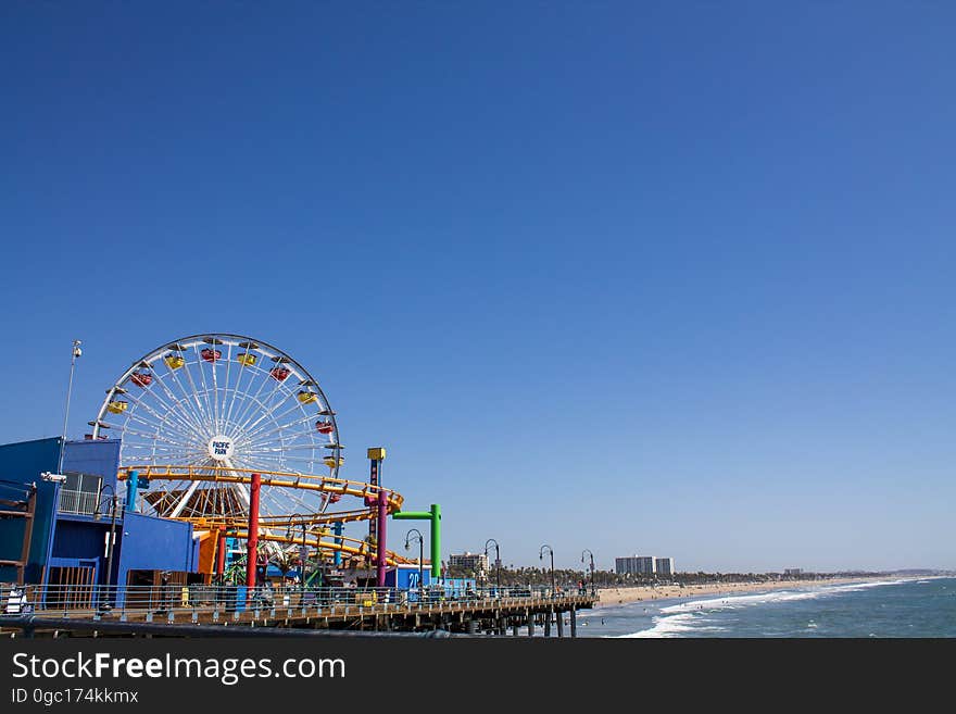 Seaside carnival with rides and Ferris Wheel on sunny day against blue skies. Seaside carnival with rides and Ferris Wheel on sunny day against blue skies.