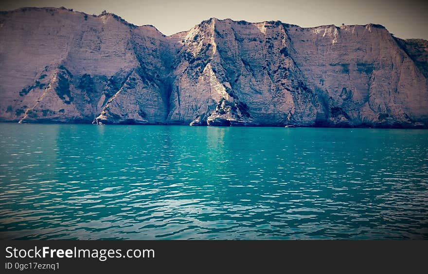 Rocky precipice along blue waters on coastal New Zealand. Rocky precipice along blue waters on coastal New Zealand.