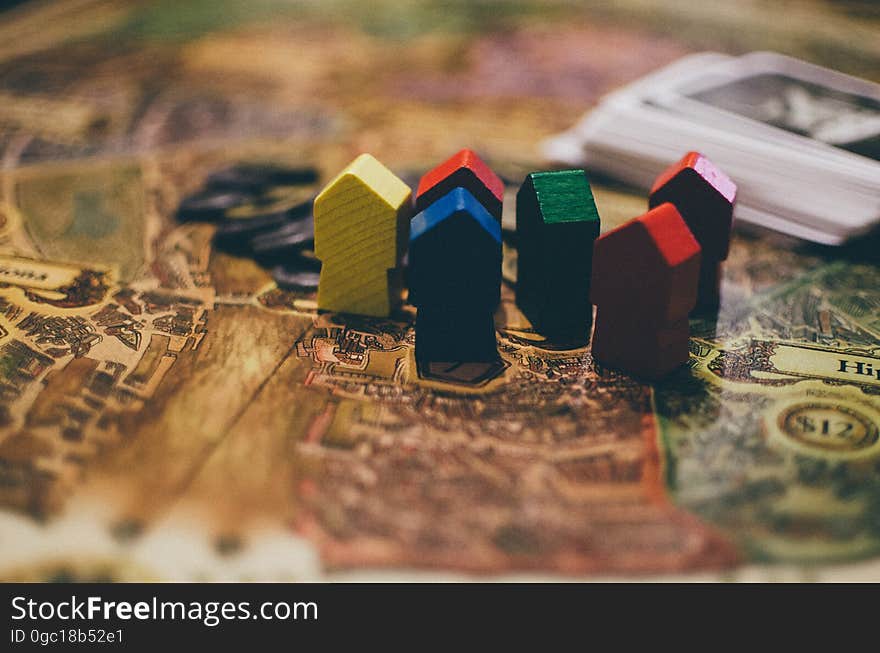 A bunch of boardgame houses and a stack of cards on table. A bunch of boardgame houses and a stack of cards on table.