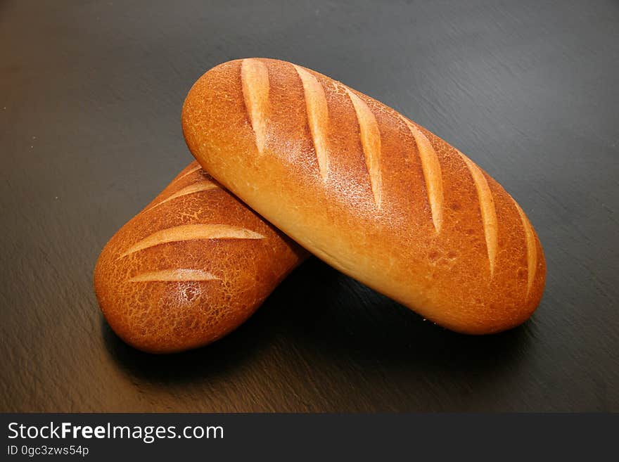 A pair of loaves of baked bread on table.