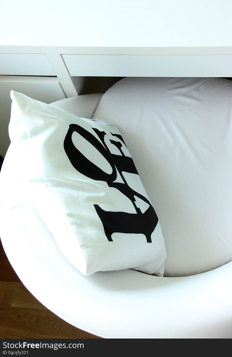 Close up of LOVE pillow on white chair.