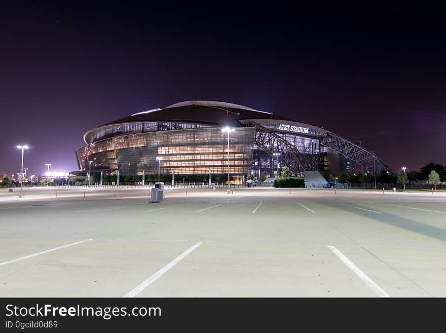 Exterior of AT&T Arena, home of Dallas Cowboys, illuminated at night with empty parking lot. Exterior of AT&T Arena, home of Dallas Cowboys, illuminated at night with empty parking lot.