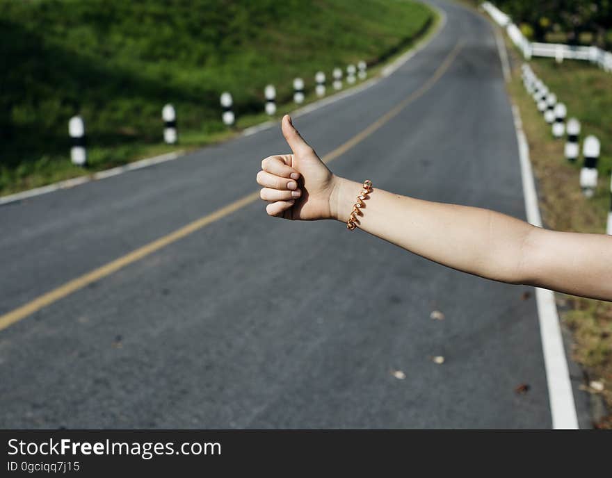 A person hitchhikes on an empty road. A person hitchhikes on an empty road.